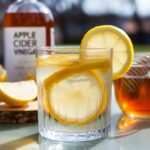 Brazilian natural Mounjaro recipe drink with apple cider vinegar, lemon slices, and honey on a wooden board