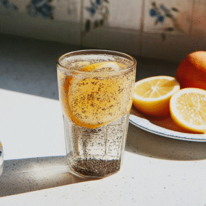 Bariatric seed tonic with chia and lemon in a clear glass, shown with fresh lemon slices in sunlight